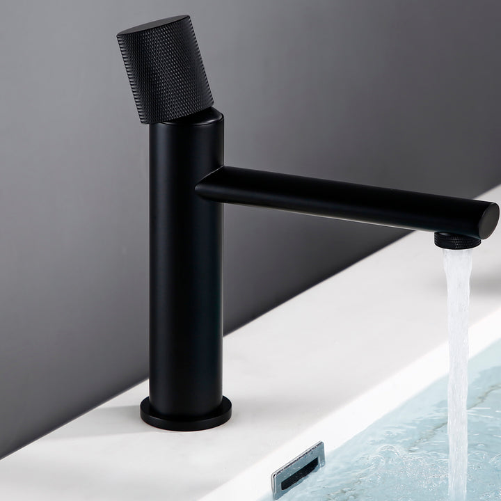 Un robinet lavabo salle de bain noir en laiton avec poignée ronde travaillée et eau qui s'écoule. Élégant et minimaliste, il apporte une touche d'originalité et de modernité à votre espace. Valve en céramique pour une durabilité maximale.