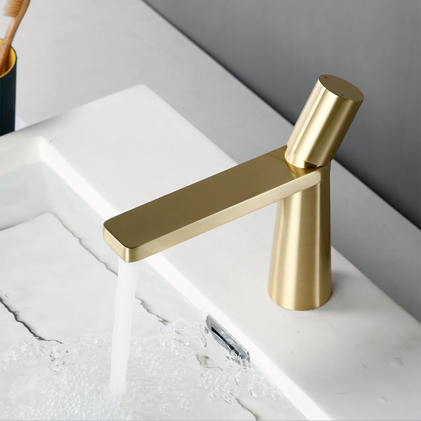 Robinet salle de bain lavabo minimaliste géométrique design en laiton doré avec eau qui coule.