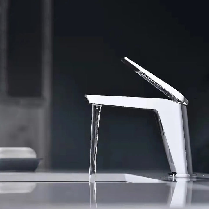 Un robinet lavabo minimaliste en laiton argenté chromé avec un mitigeur rectangulaire sur le dessus. Filtre aérateur nid d'abeille pour une sortie d'eau fluide et agréable. Parfait pour une salle de bain au design minimaliste et une finition argentée impeccable.