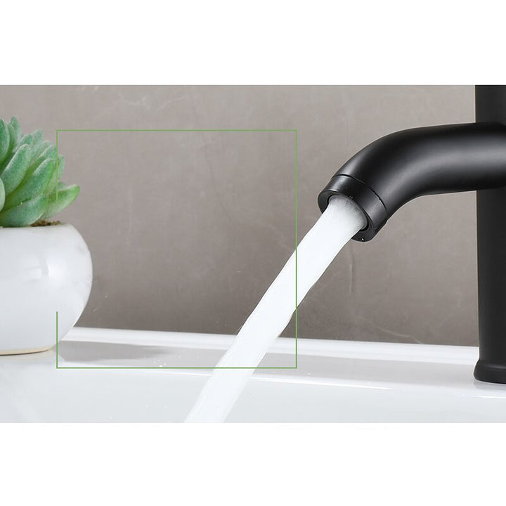 Un robinet lavabo minimaliste en noir mat avec de l'eau qui coule. Design moderne et élégant pour salle de bain. Matériau en acier inoxydable durable. Poignée ergonomique pour une manipulation facile. Disponible en deux hauteurs pour s'adapter à votre vasque.