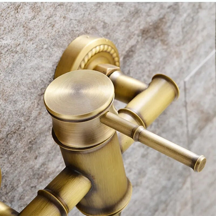 Un robinet de douche mural en bambou avec un pommeau flexible doré bronze brossé.