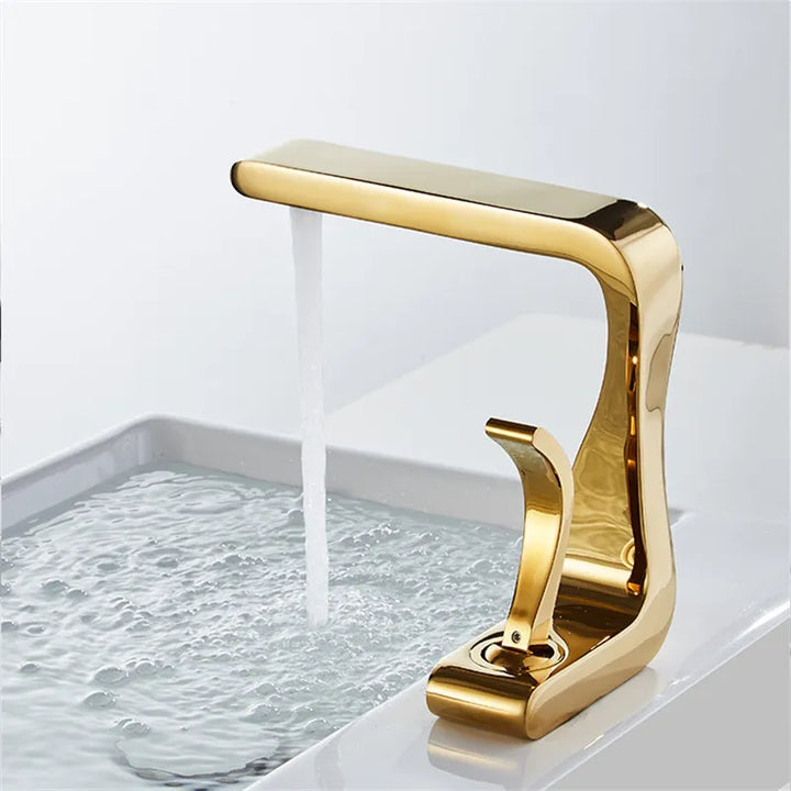 Un robinet lavabo salle de bain doré en laiton avec de l'eau qui s'écoule. Design incurvé et élégant, parfait pour ajouter une touche de luxe à votre salle de bain.