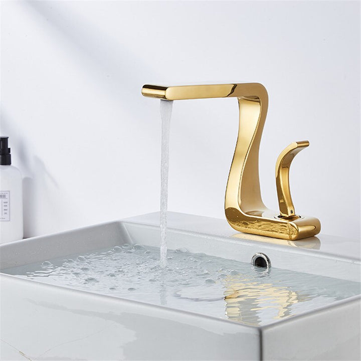 Robinet lavabo salle de bain mitigeur design incurvé en laiton doré avec eau qui s'écoule. Ajoute une touche de luxe à votre salle de bain.