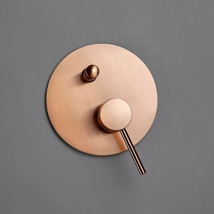 Un gros plan d'une poignée de robinet en cuivre avec un bouton et un objet circulaire en métal.