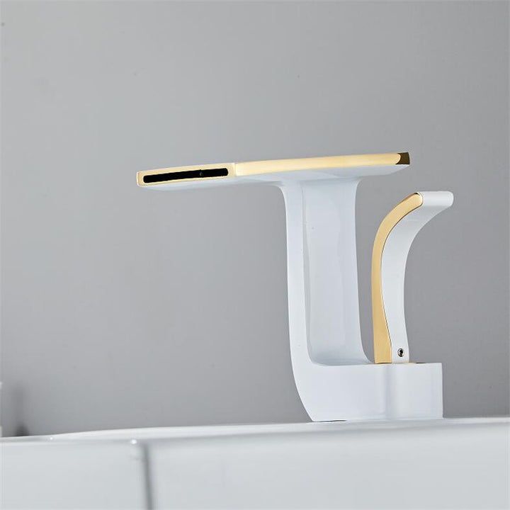 Un robinet lavabo salle de bain plat géométrique mitigeur design en laiton blanc avec finitions dorées. Poignée ondulée, bec rectangulaire. Ecoulement en cascade pour une expérience relaxante. Dimensions : 14,5 x 12,5 cm. Poids : <2 kg.