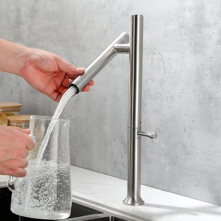 Un personne verse de l'eau dans un verre avec le Robinet cuisine évier design fin style bambou - Argenté de l'Atelier Du Robinet.