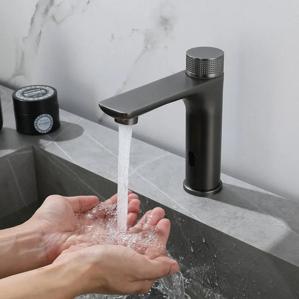 Dans une salle de bain en marbre, un robinet noir est installé. Il est moderne avec une poignée ronde de mitigeur. Il est tactile. Une femme met ses mains sous l'eau.