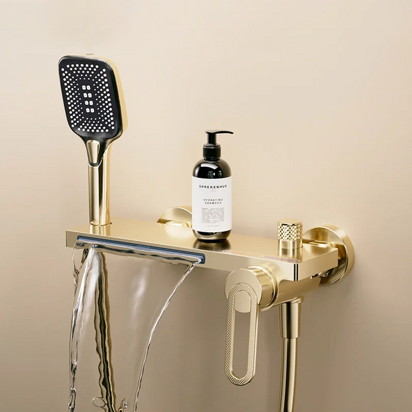 Dans une salle de bain, un robinet pour baignoire avec douchette carré et cascade doré brossé est installé. Le style est moderne.