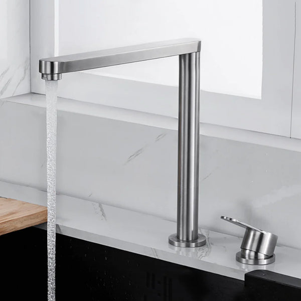 Dans une cuisine, un robinet minimaliste argenté brossé est installé. Le robinet est rabatable avec une poignée déportée. 