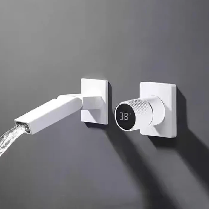 Un robinet pour lavabo de salle de bain est blanc et encastré au mur. Il est mural, minimaliste avec un bec pivotant à 360° et à côté une poignée avec affichage de la température numérique.