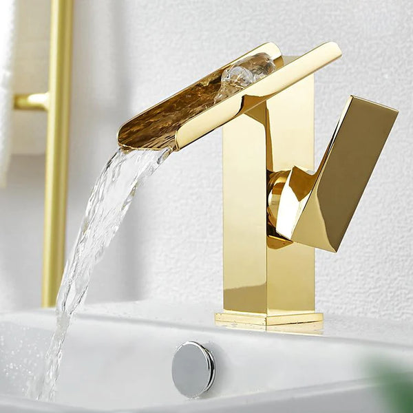 Un robinet lavabo doré avec de l'eau qui en sort, design rectangulaire cascade - Laiton. Parfait pour votre salle de bain contemporaine.