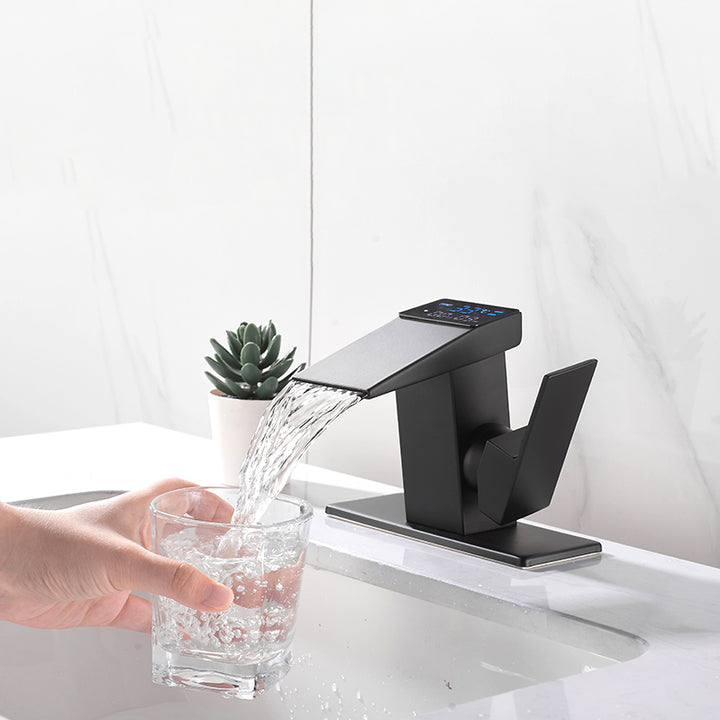 Un robinet thermostatique à affichage numérique en laiton noir mat, avec une personne versant de l'eau dans un verre. Un design contemporain avec des lignes nettes. Contrôle optimal de la température et de la durée de l'écoulement de l'eau en cascade. Parfait pour votre salle de bain.