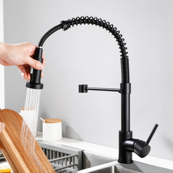 Un homme lave la vaisselle sous un robinet avec douchette cuisine évier noir mat en laiton. Hauteur de 43 cm, jet multijet puissant, contrôle manuel de la température.